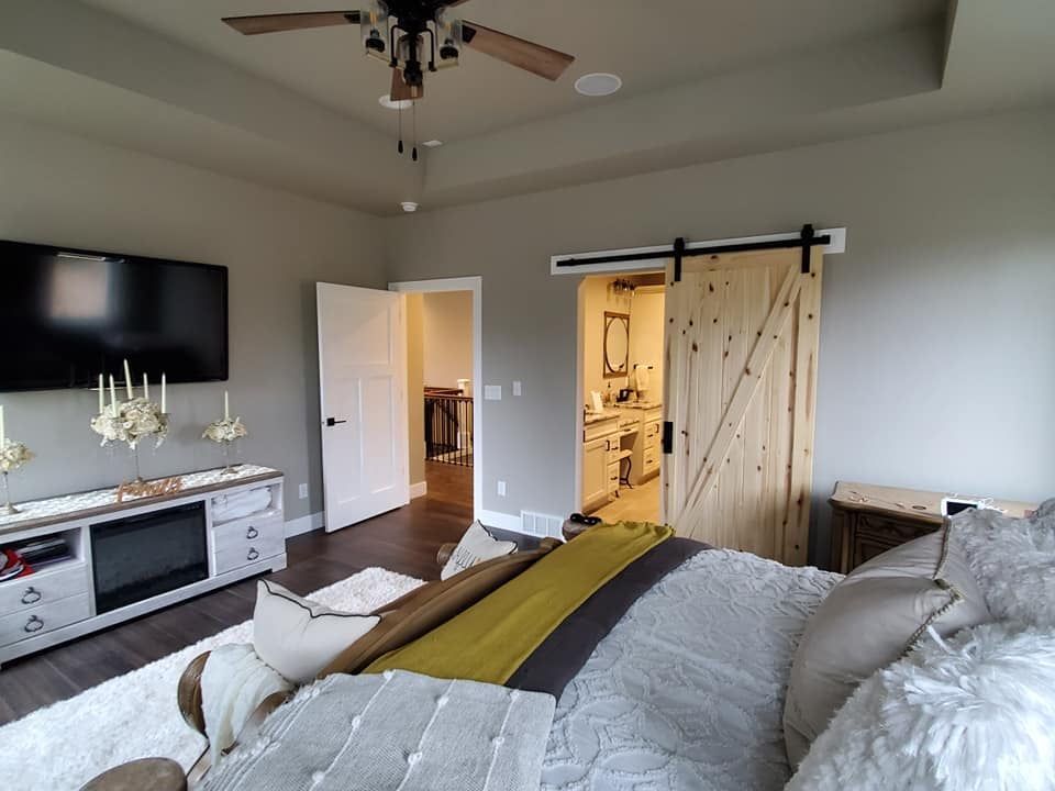 Bedroom with large bed, TV on dresser, and barn-style sliding door open to adjoining room.