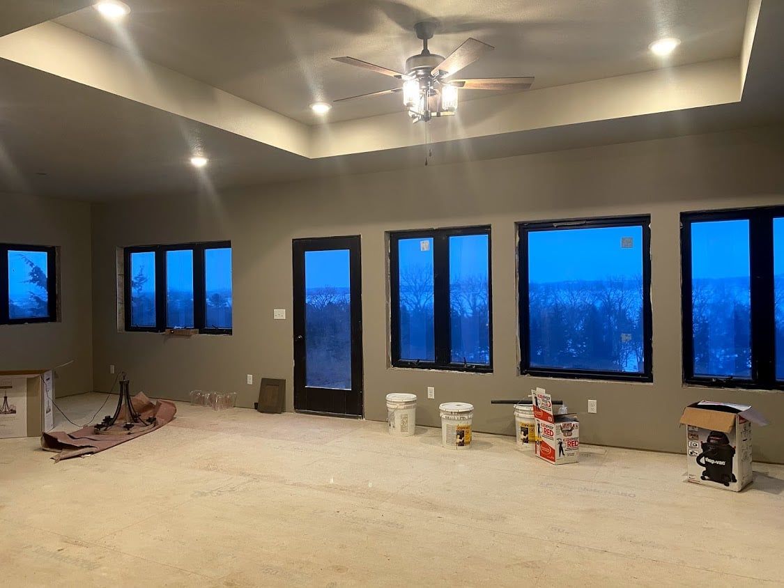 Empty living room with carpet, recessed ceiling lights, and large blue-tinted windows.