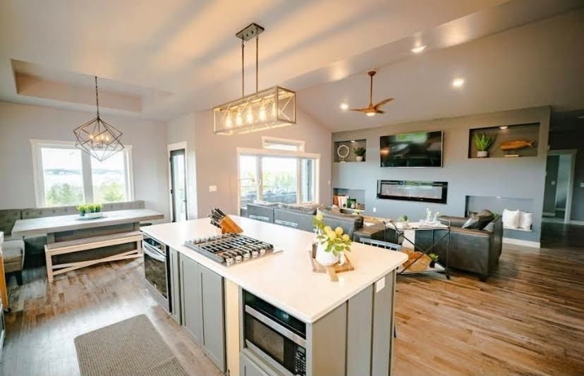 Bright open-concept kitchen and living room with wood floors, island, dining table, and gray sofa