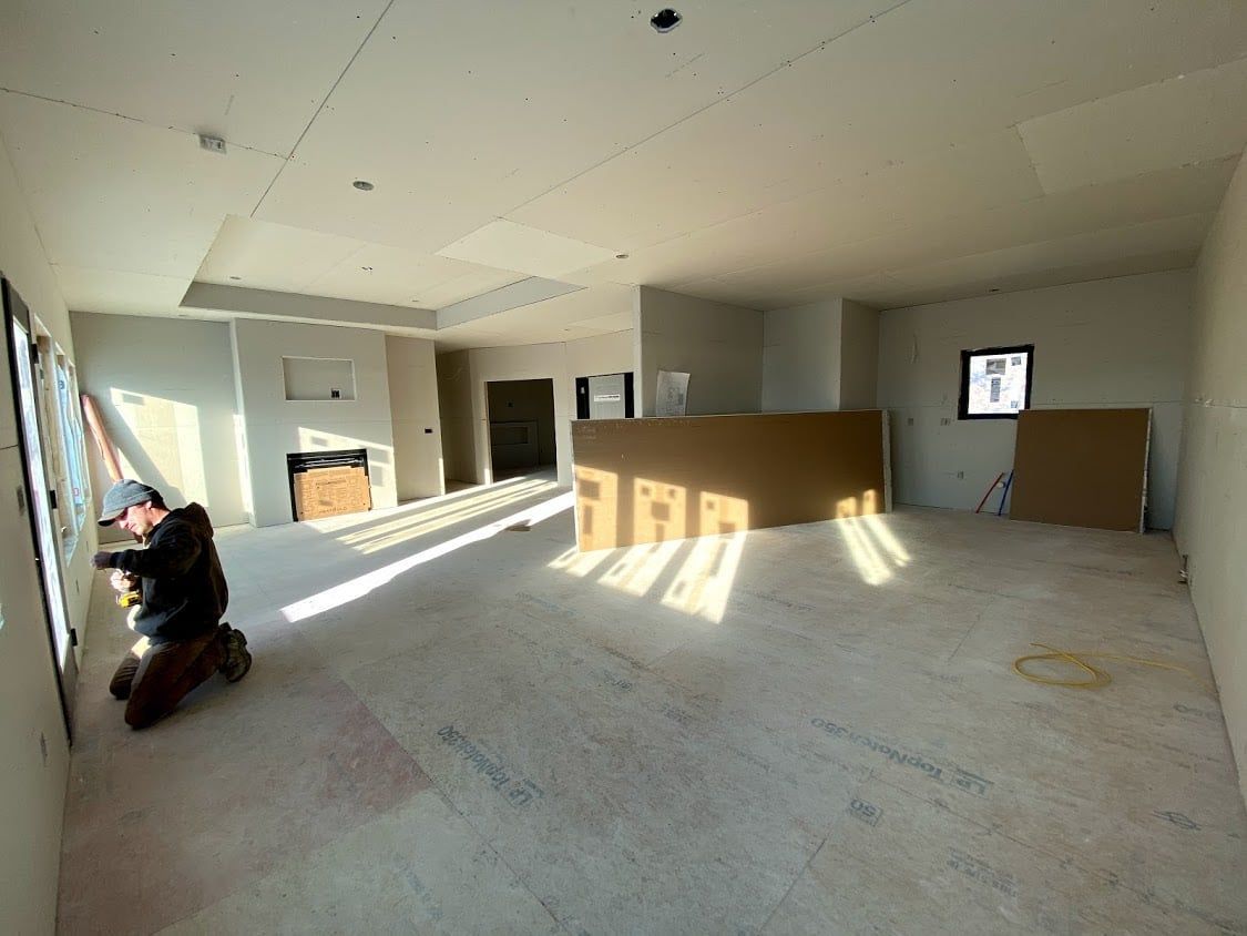 Empty unfinished room with exposed flooring, sunlight, and a wheelchair near the left wall