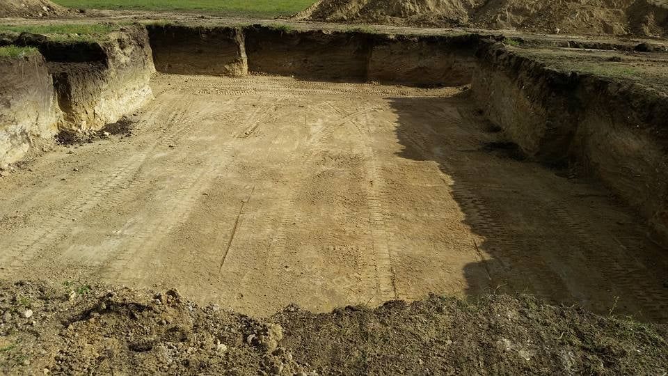 Excavated dirt trench with rough earthen walls and a flat, cleared center