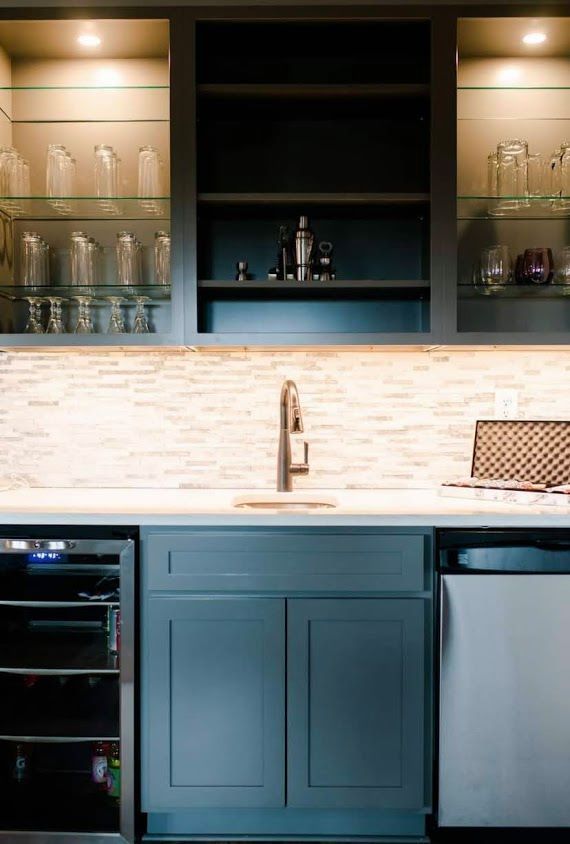 Blue kitchen cabinets with open shelves, under-cabinet lights, sink, wine fridge, and dishwasher.