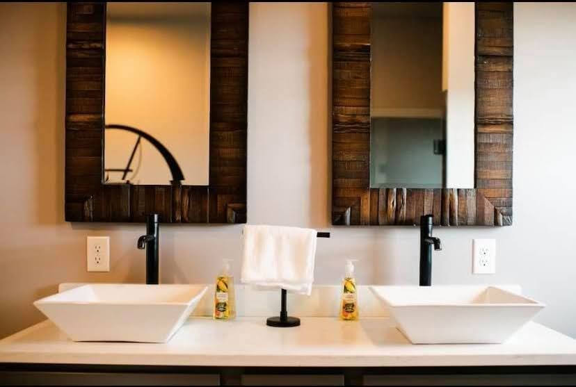 Modern bathroom vanity with two vessel sinks, mirrors, and black faucets