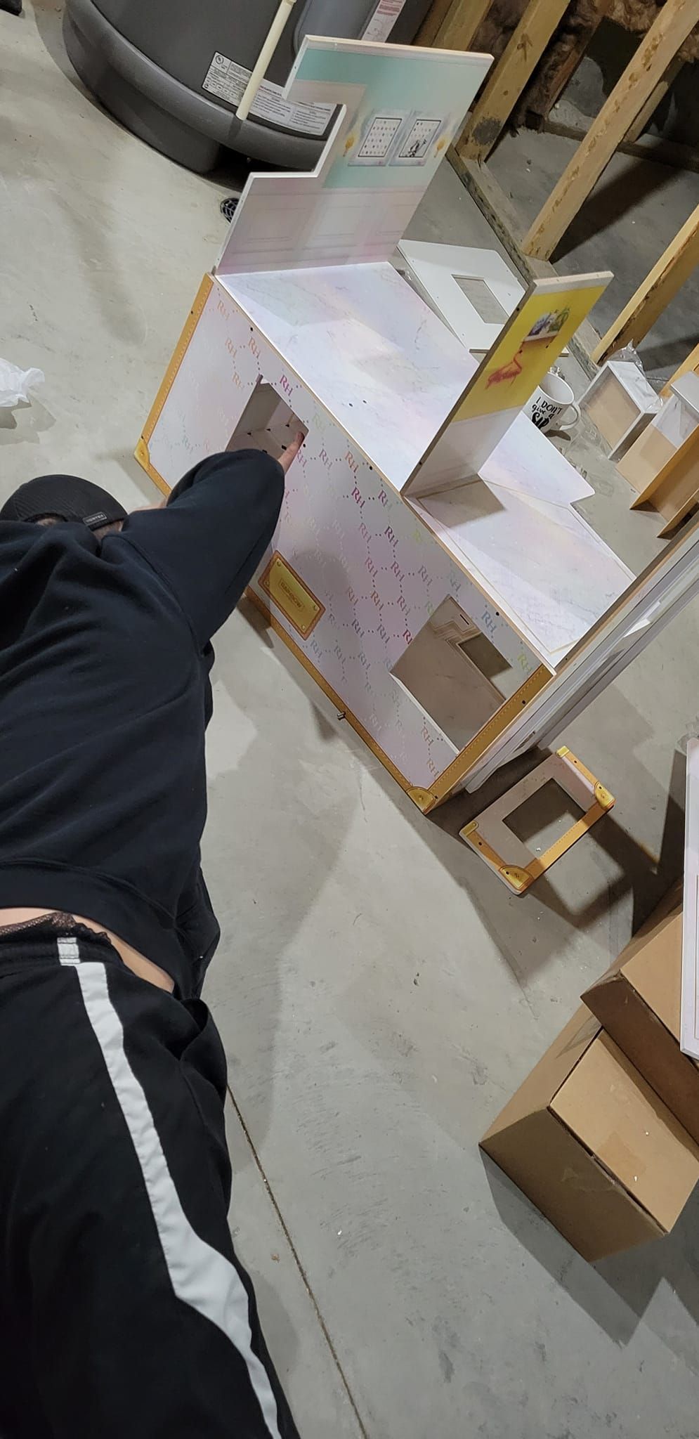Person pointing at stacked white and brown boxes in a warehouse aisle.