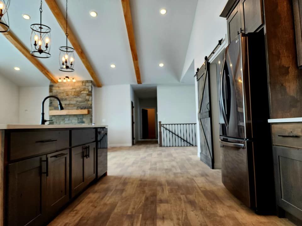 Modern kitchen with dark cabinets, pendant lights, wood floors, and stainless steel appliances