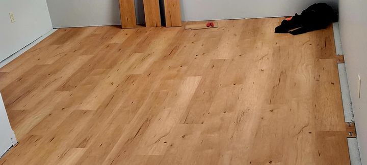 Empty wooden room with a dark cat lying in the back-right corner