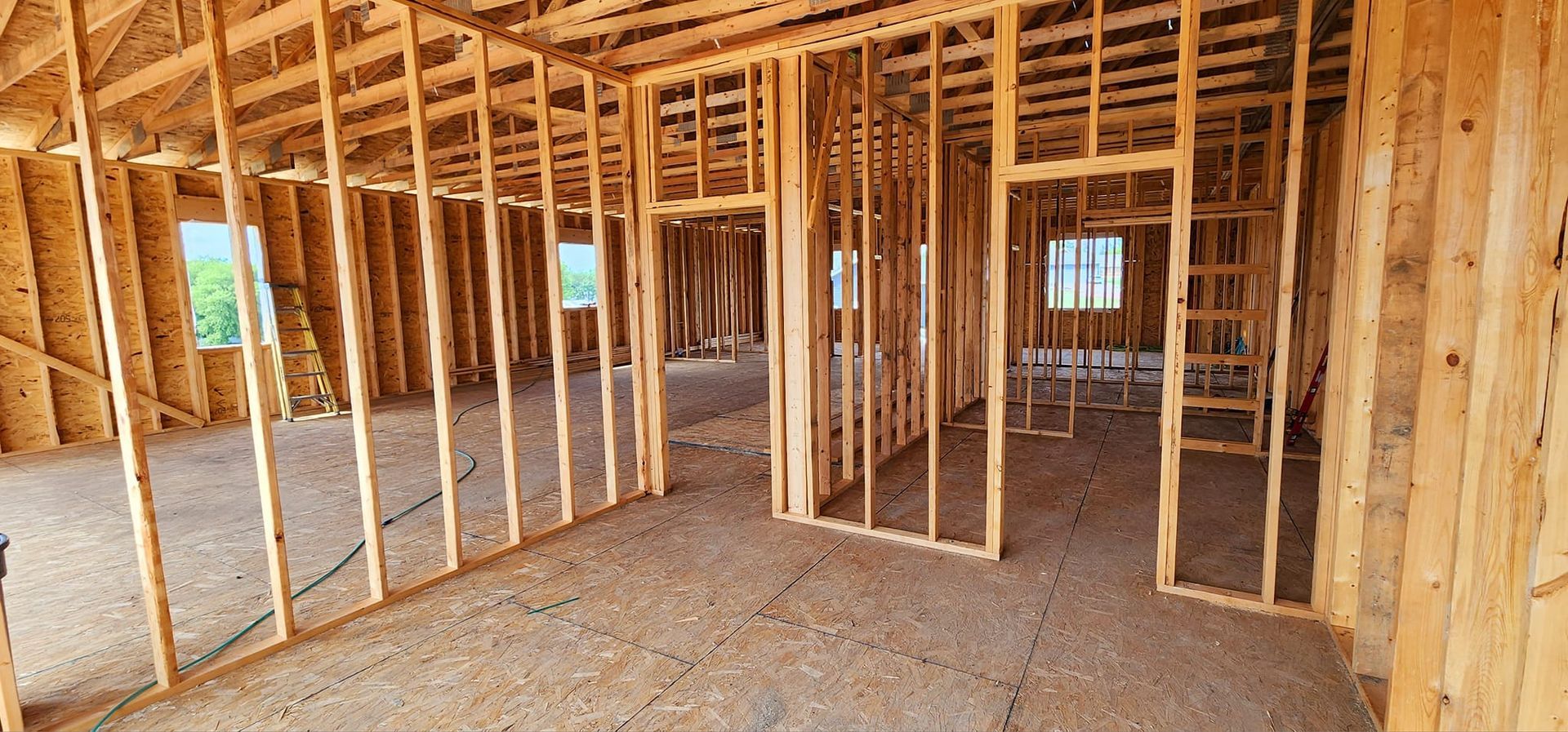 Interior of a house under construction, with exposed wooden framing and unfinished walls and floor.