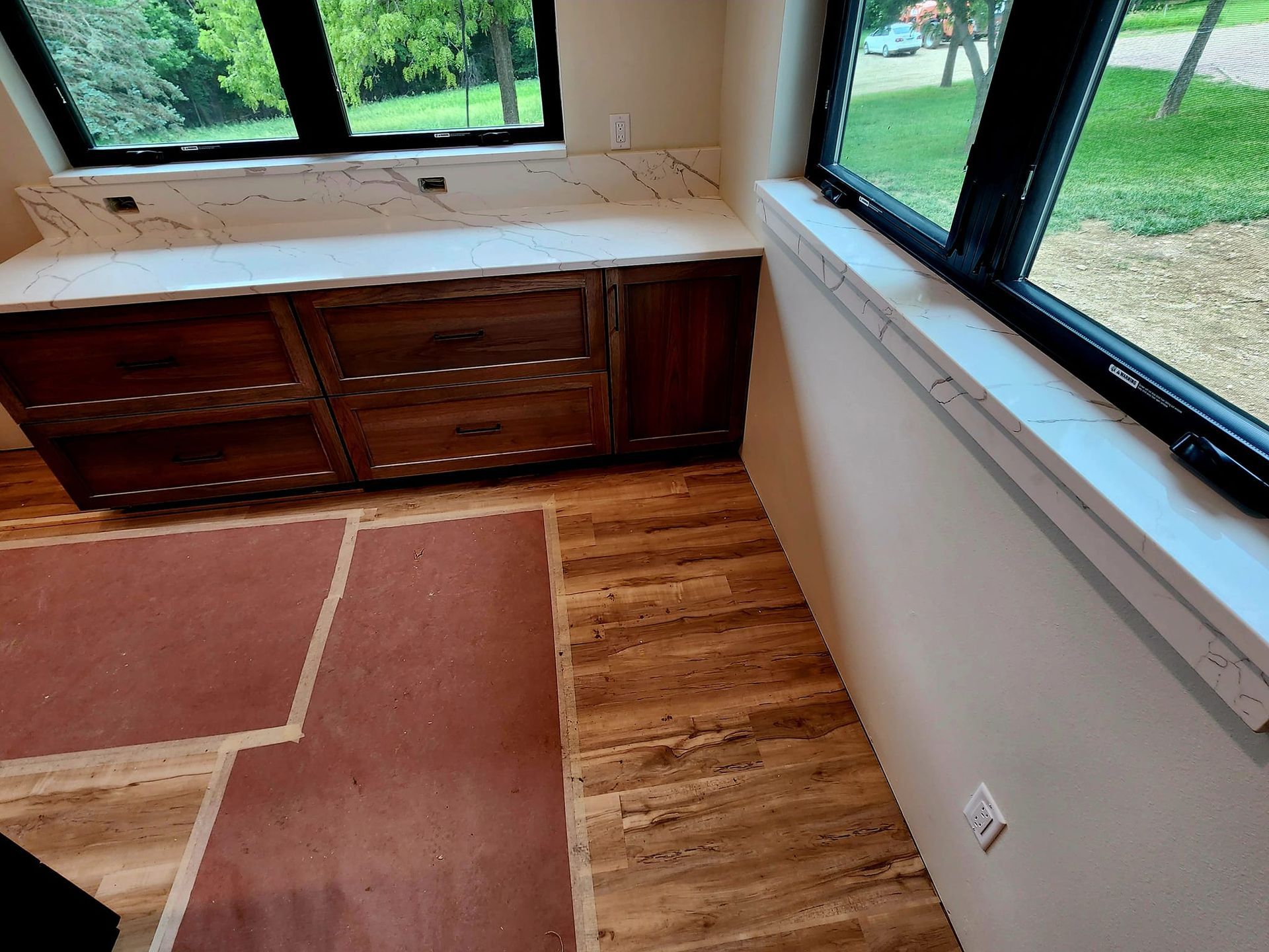 Empty room with wood-look floor, white walls, windows, and built-in cabinets along one wall