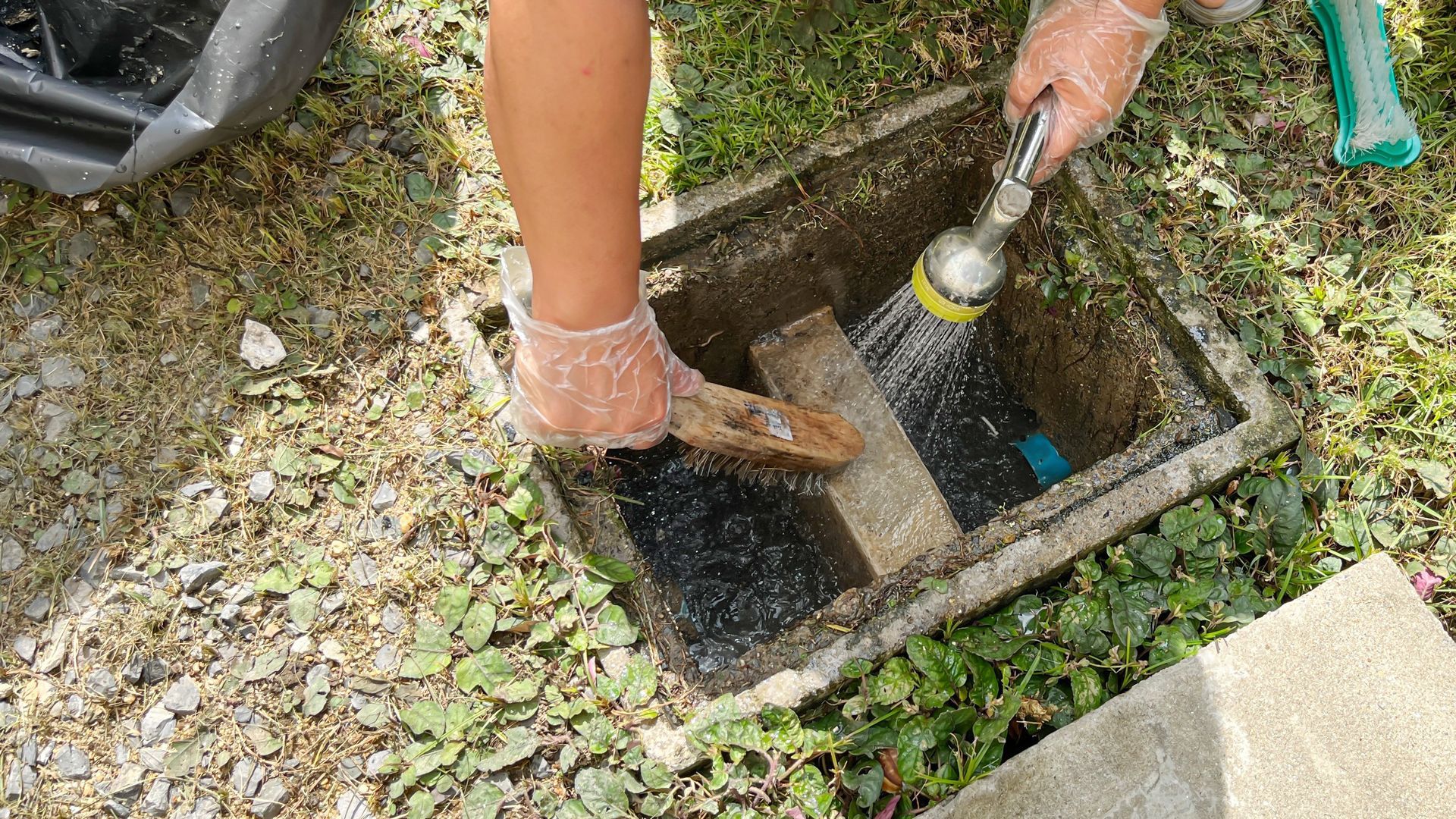 Technician cleaning an outdoor storm drain to improve drainage Technician cleaning an outdoor storm drain to improve drainage