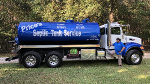 A blue septic tank with white text, next to a smiling man, on a forest.