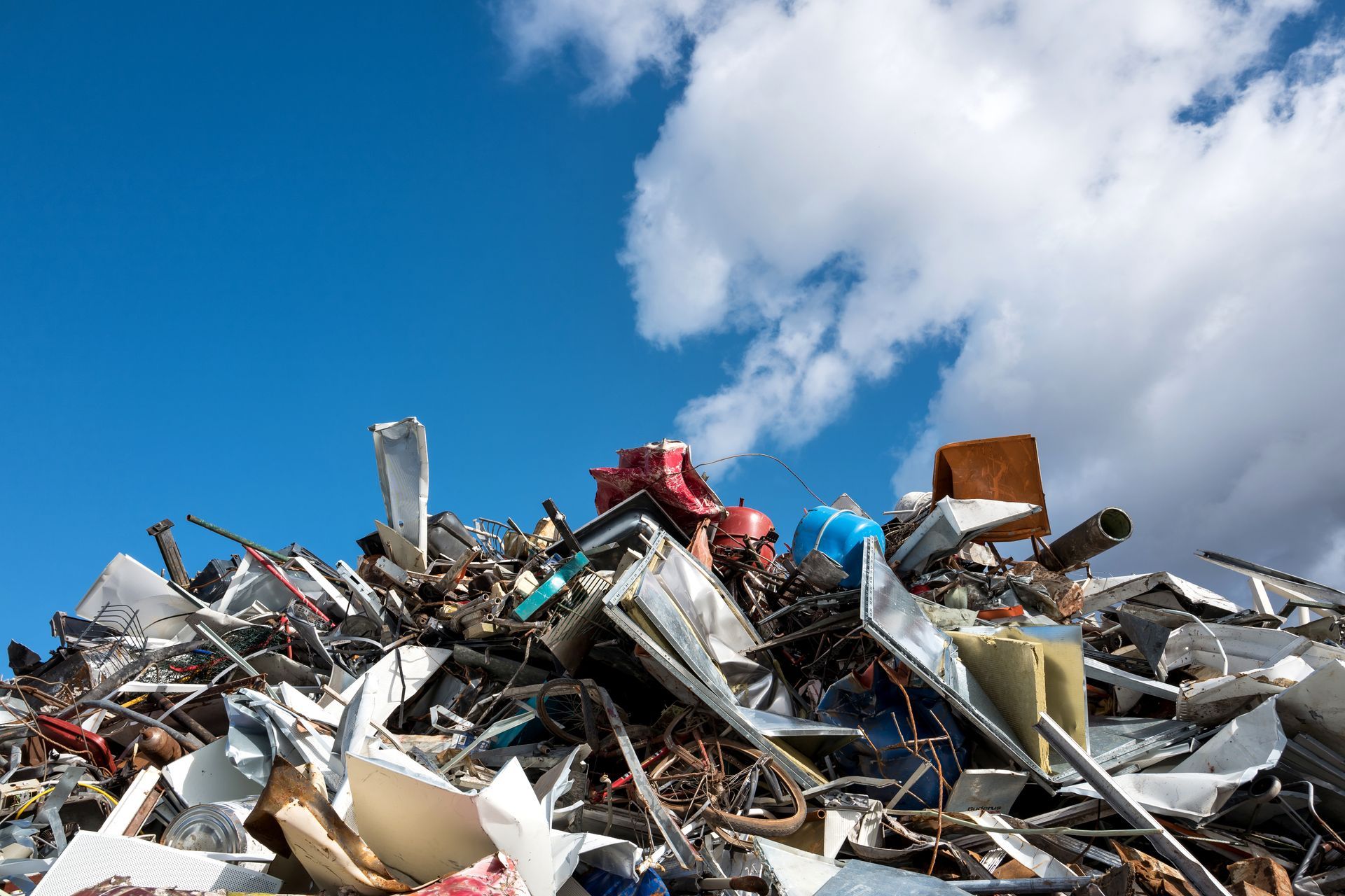 Scrap metal heap at recycling yard, highlighting steel recycling with clear blue sky backdrop.