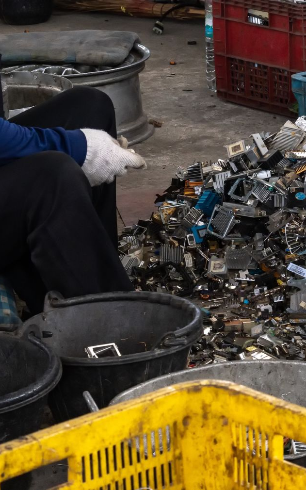 Portrait of worker with gloved hands, standing in front of scrap in a metal recycling facility. Portrait of worker with gloved hands, standing in front of scrap in a metal recycling facility.