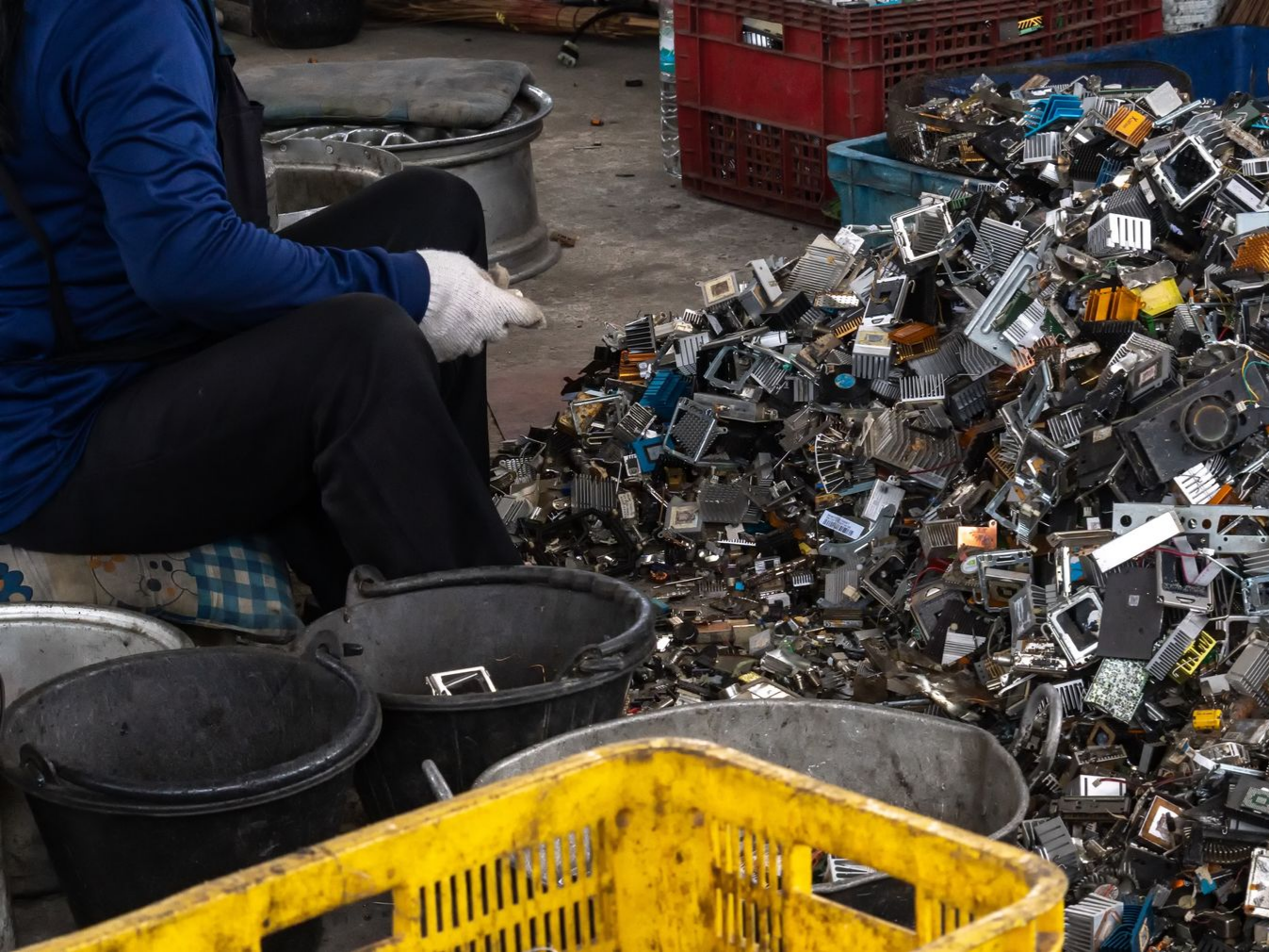 Portrait of worker with gloved hands, standing in front of scrap in a metal recycling facility. Portrait of worker with gloved hands, standing in front of scrap in a metal recycling facility.