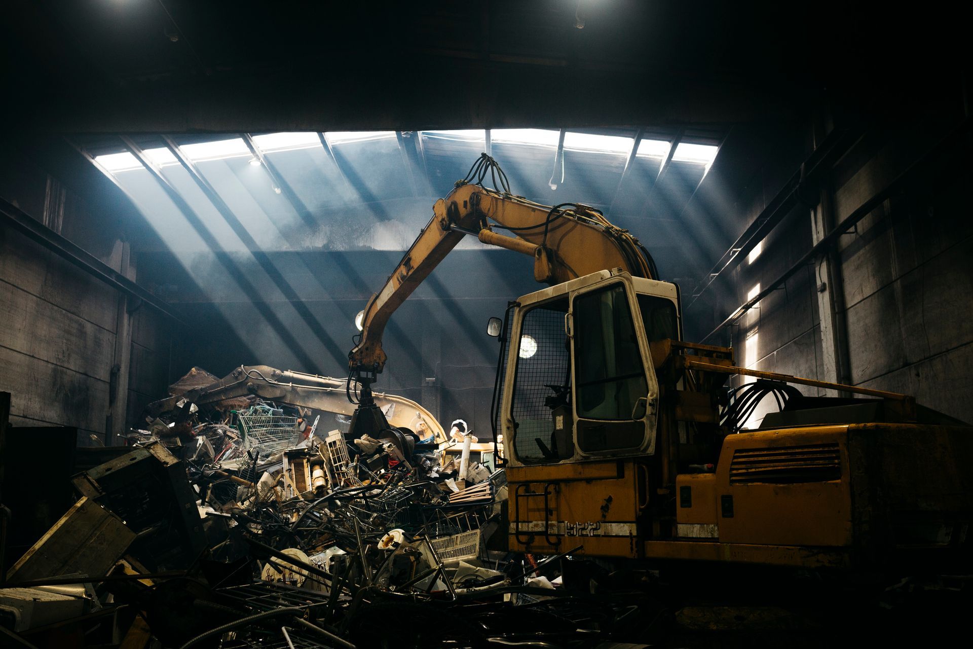 A hydraulic mechanical grabber illuminated with a ray of light in a scrap metal yard