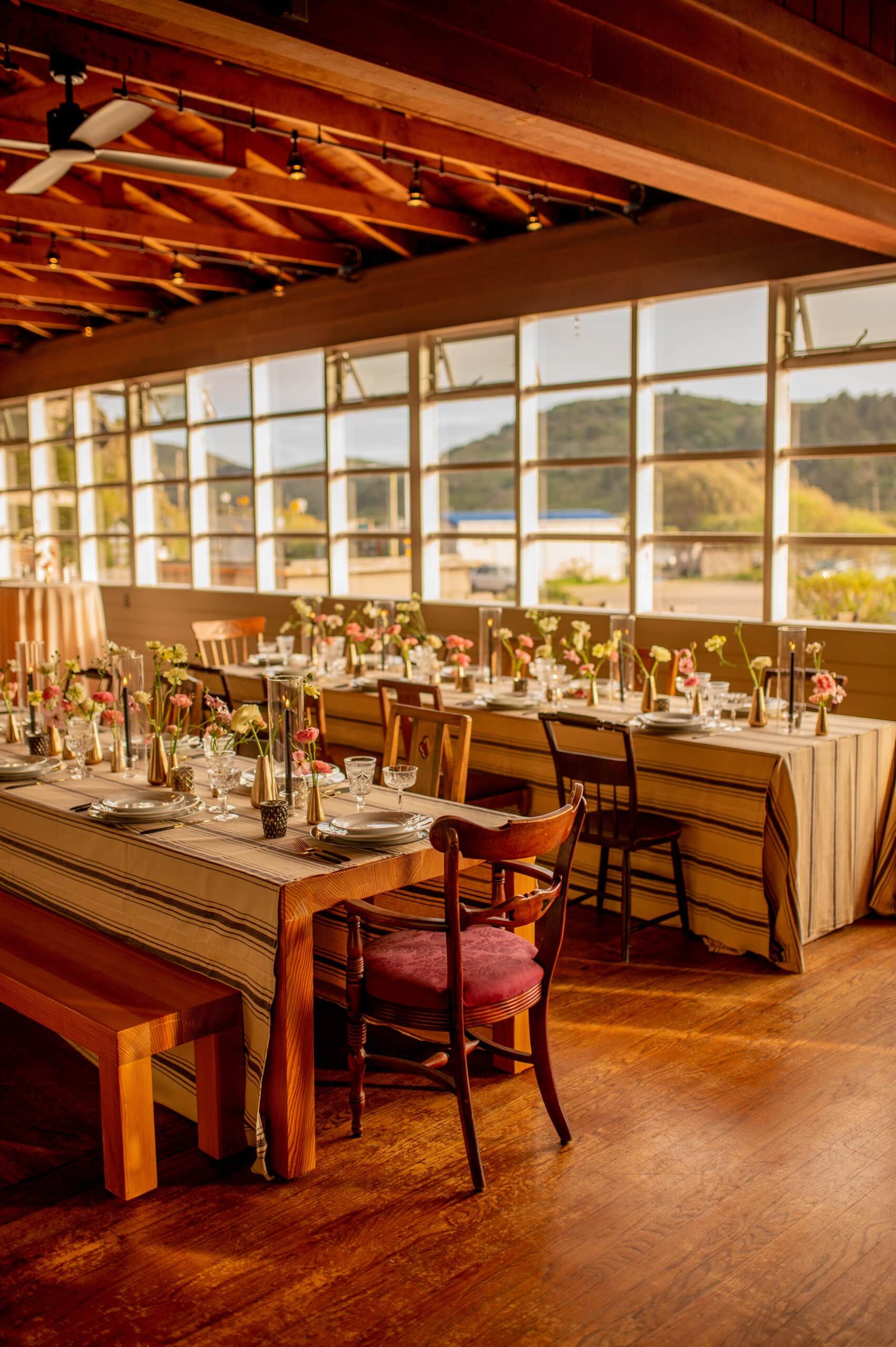 Event space with tables set for a meal near a large window overlooking a landscape.
