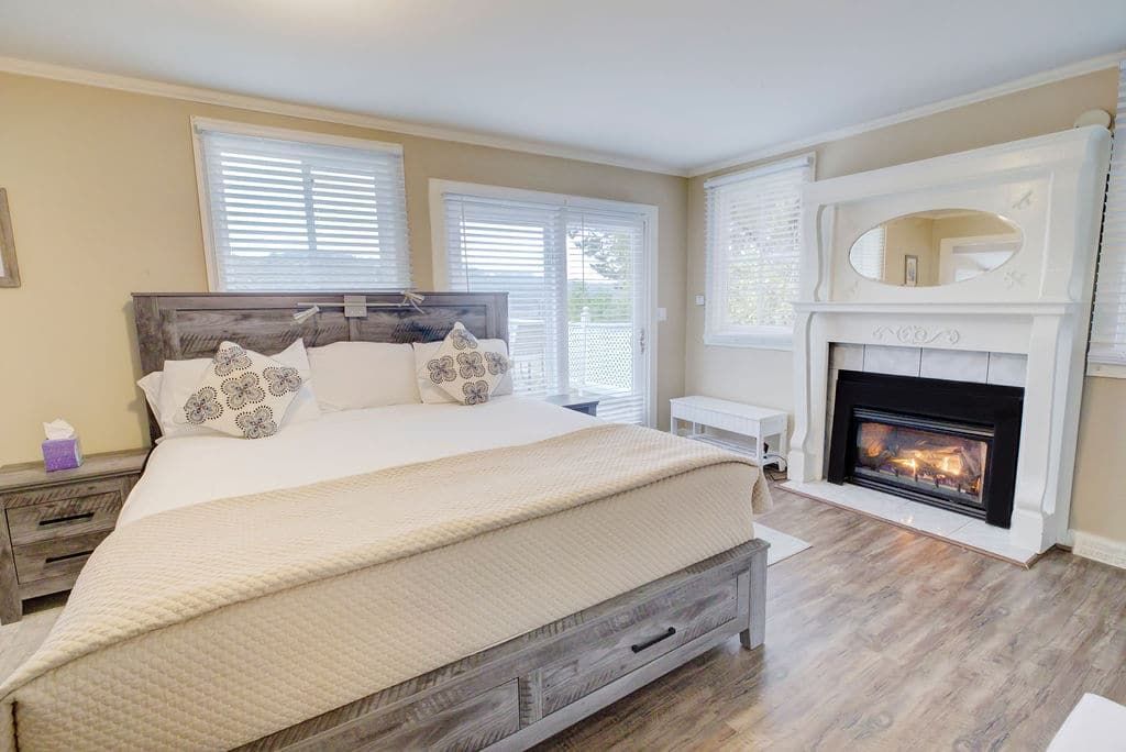 Bedroom with bed, fireplace, windows, and sliding door.