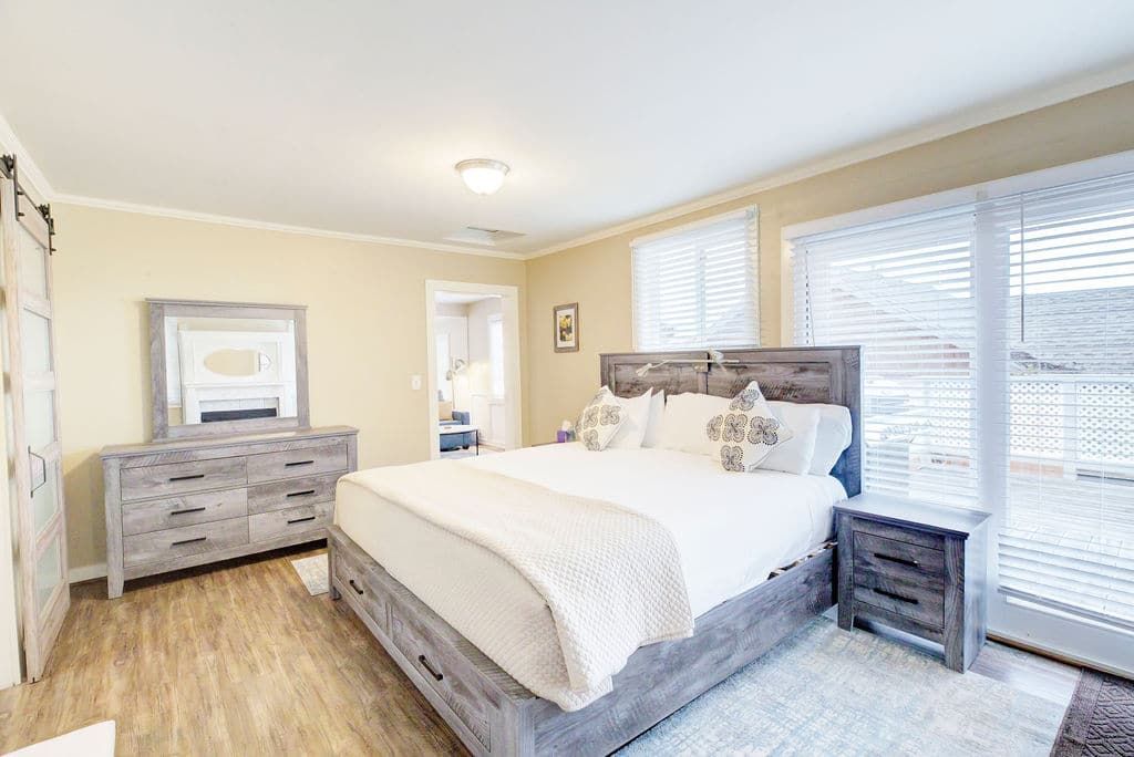 Bedroom with a large bed, dresser, nightstand, and sliding doors to an outdoor area.