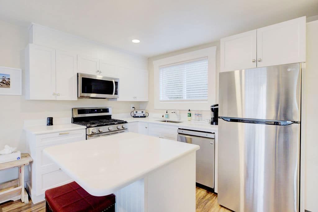 White kitchen with stainless steel appliances, white cabinets, and a small island.