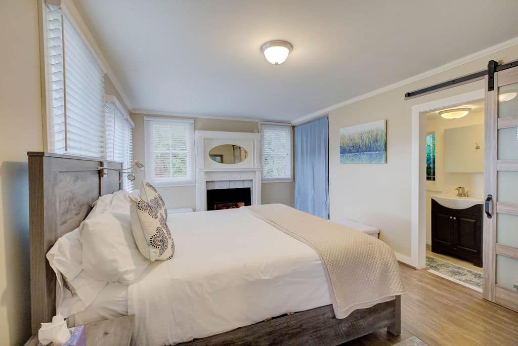 Bedroom with bed, fireplace, and bathroom with sliding door.