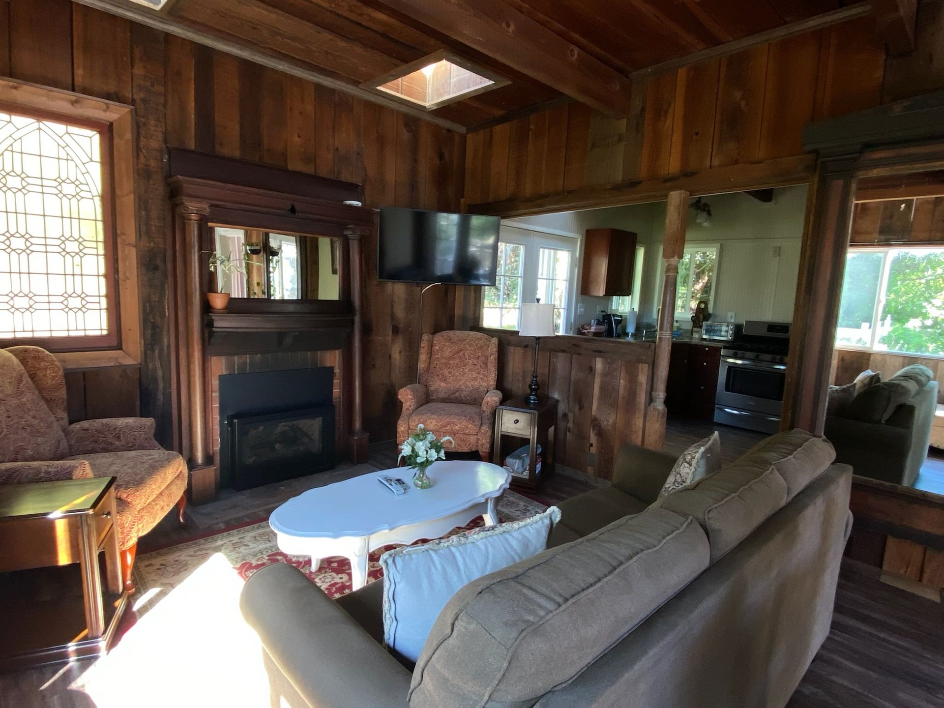Cozy living room with wood paneling, fireplace, and two armchairs; a couch, and a small TV.