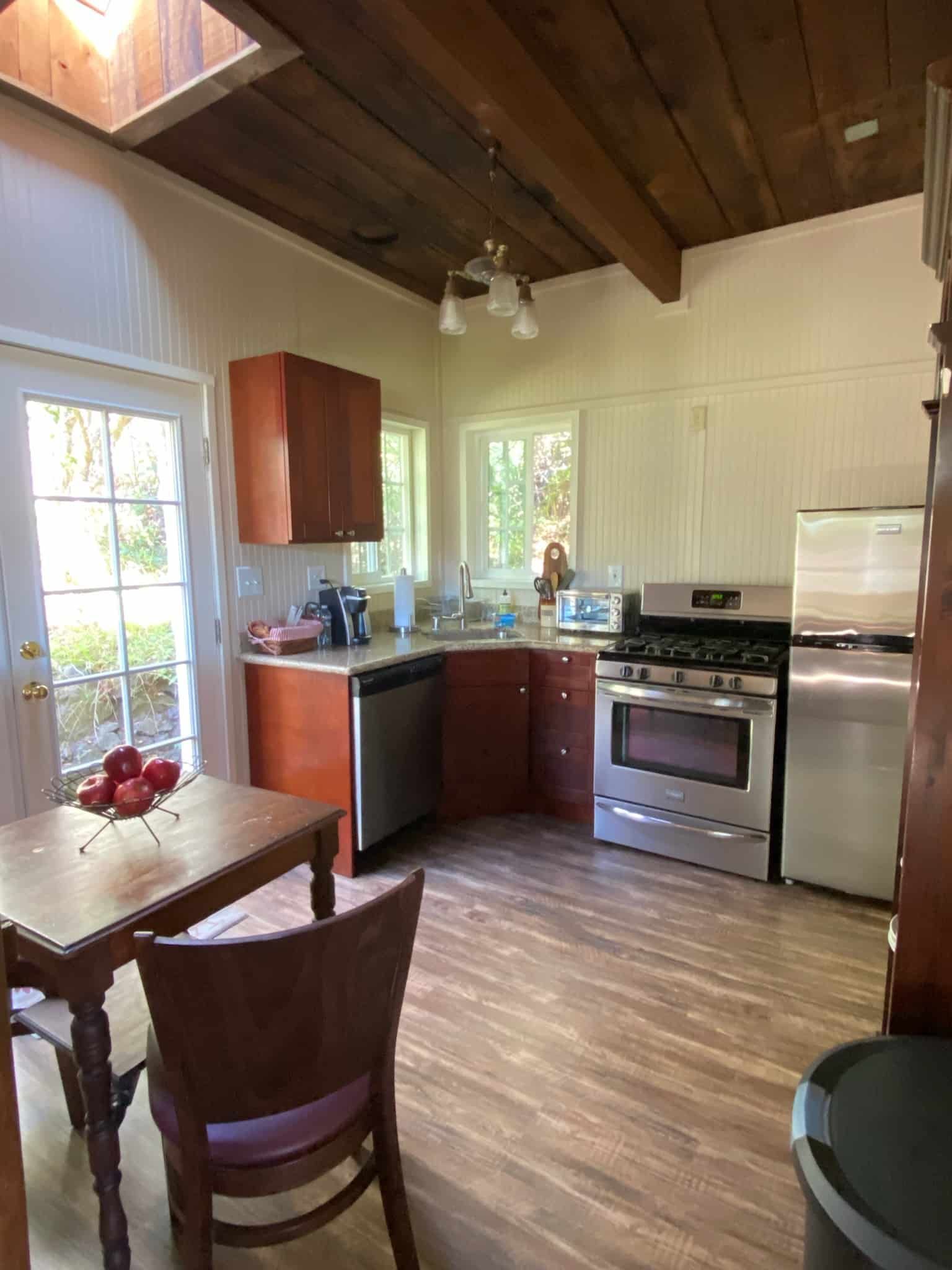 Kitchen with wooden cabinets, stainless steel appliances, and a wooden table. Door leads outside.