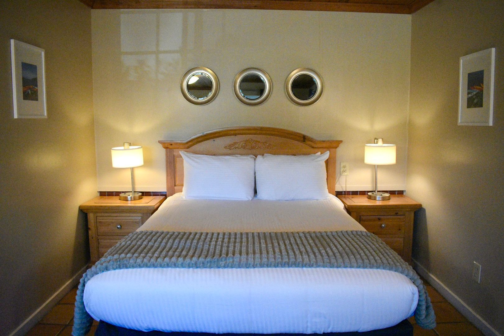 Bedroom with queen bed, nightstands, lamps, and three round mirrors above the headboard.