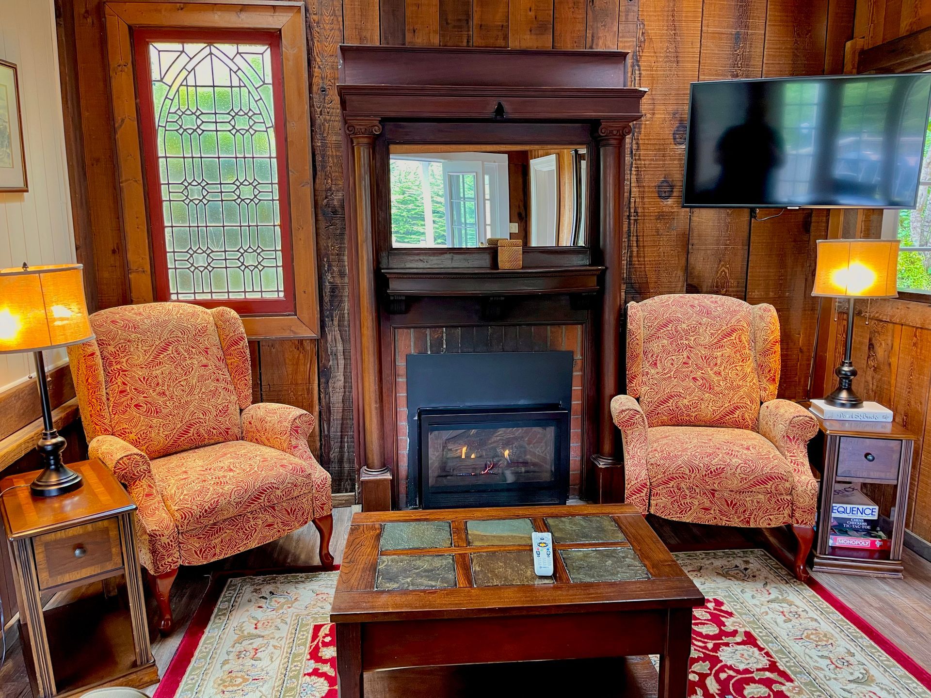 Cozy living room with dark wood paneling, a chandelier, and a round table with flowers.