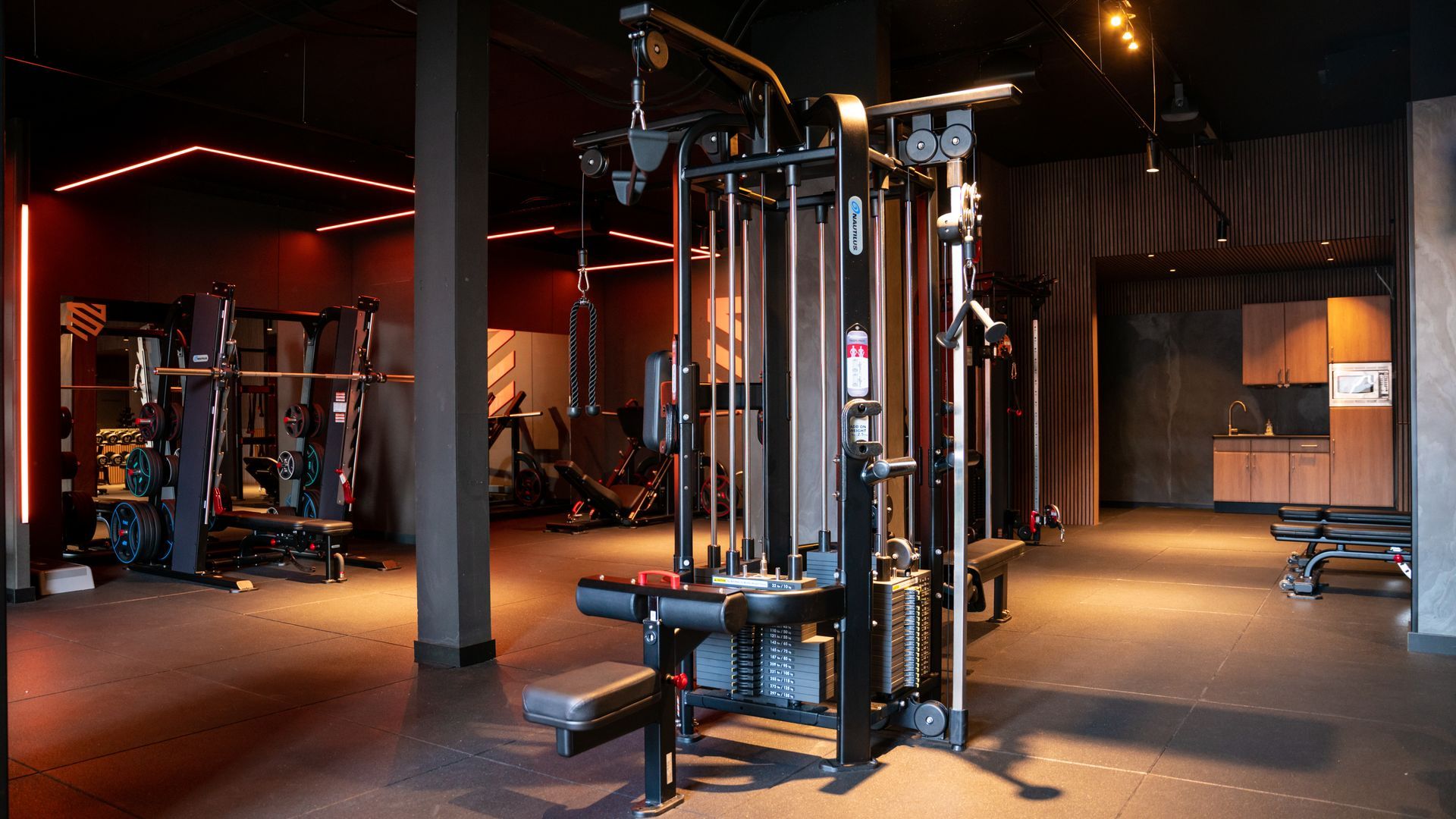 Man rent op een loopband in een sportschool, draagt ​​een groen jack en een grijze joggingbroek.