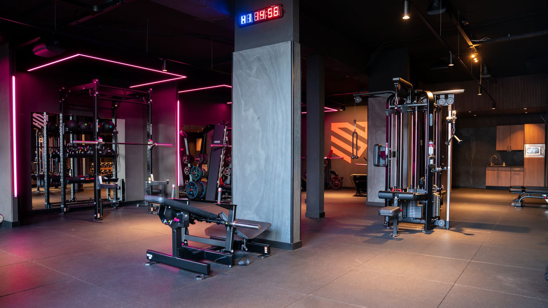 Rijen zwarte kettlebells op de vloer van een sportschool, met een rood metalen rek op de achtergrond.