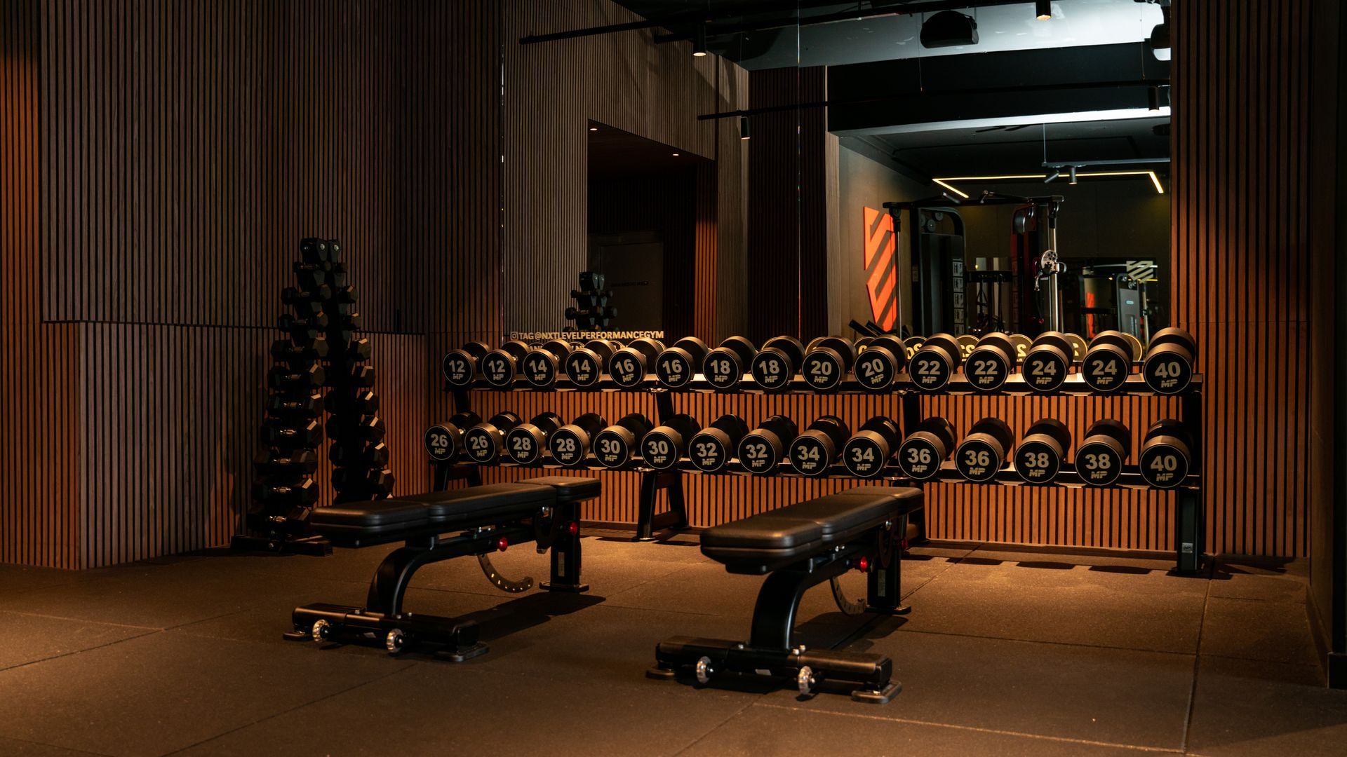 Een fitnesstrainer helpt een man met push-ups in een sportschool. De trainer draagt ​​zwart en oranje, de man in het zwart.