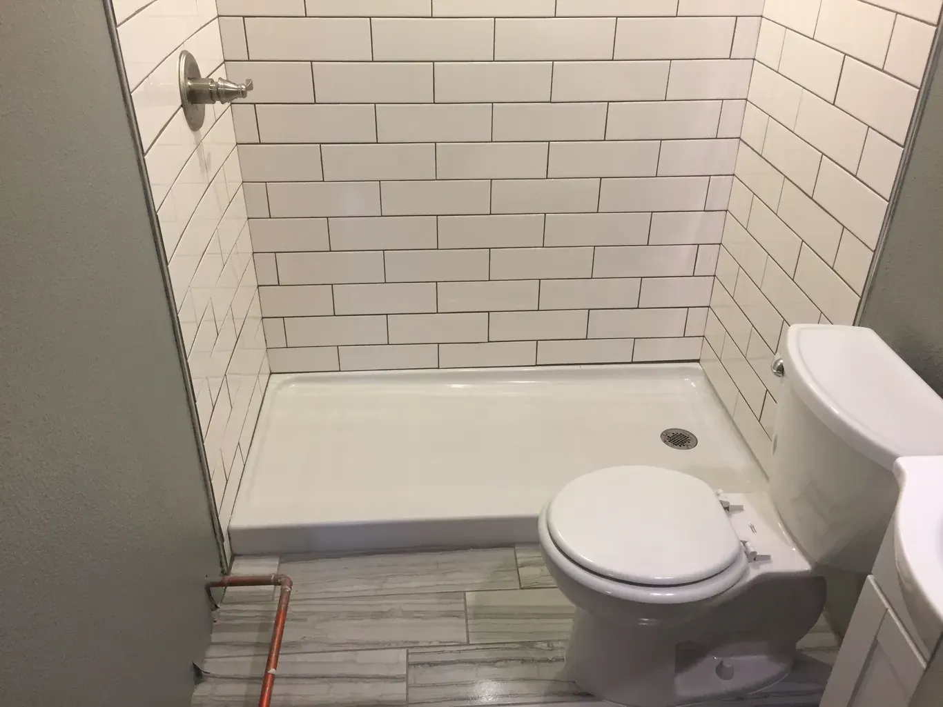 A bathroom with a toilet , sink and shower.