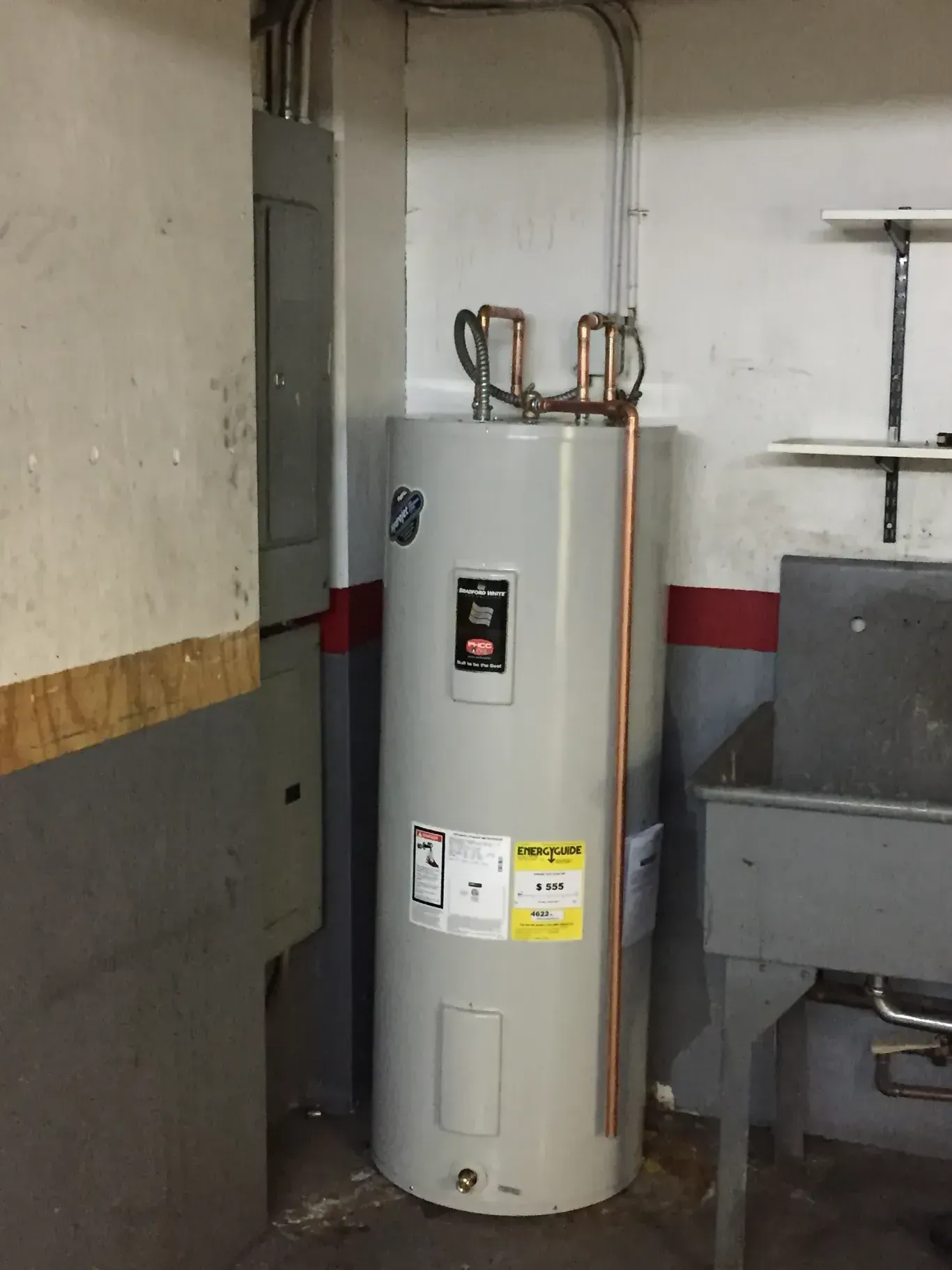 A water heater is sitting in a room next to a sink.