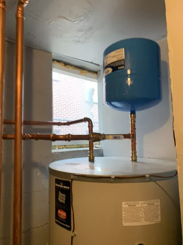 A water heater is sitting in a room next to a window.