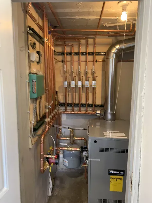 A room with a boiler and copper pipes in it.