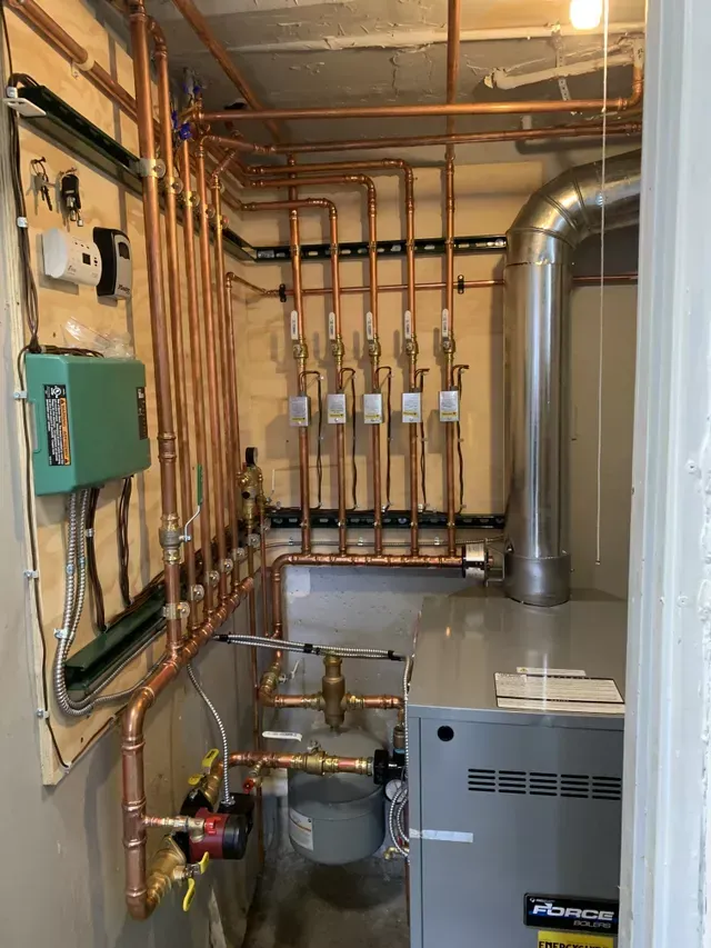 A room with a boiler and copper pipes in it