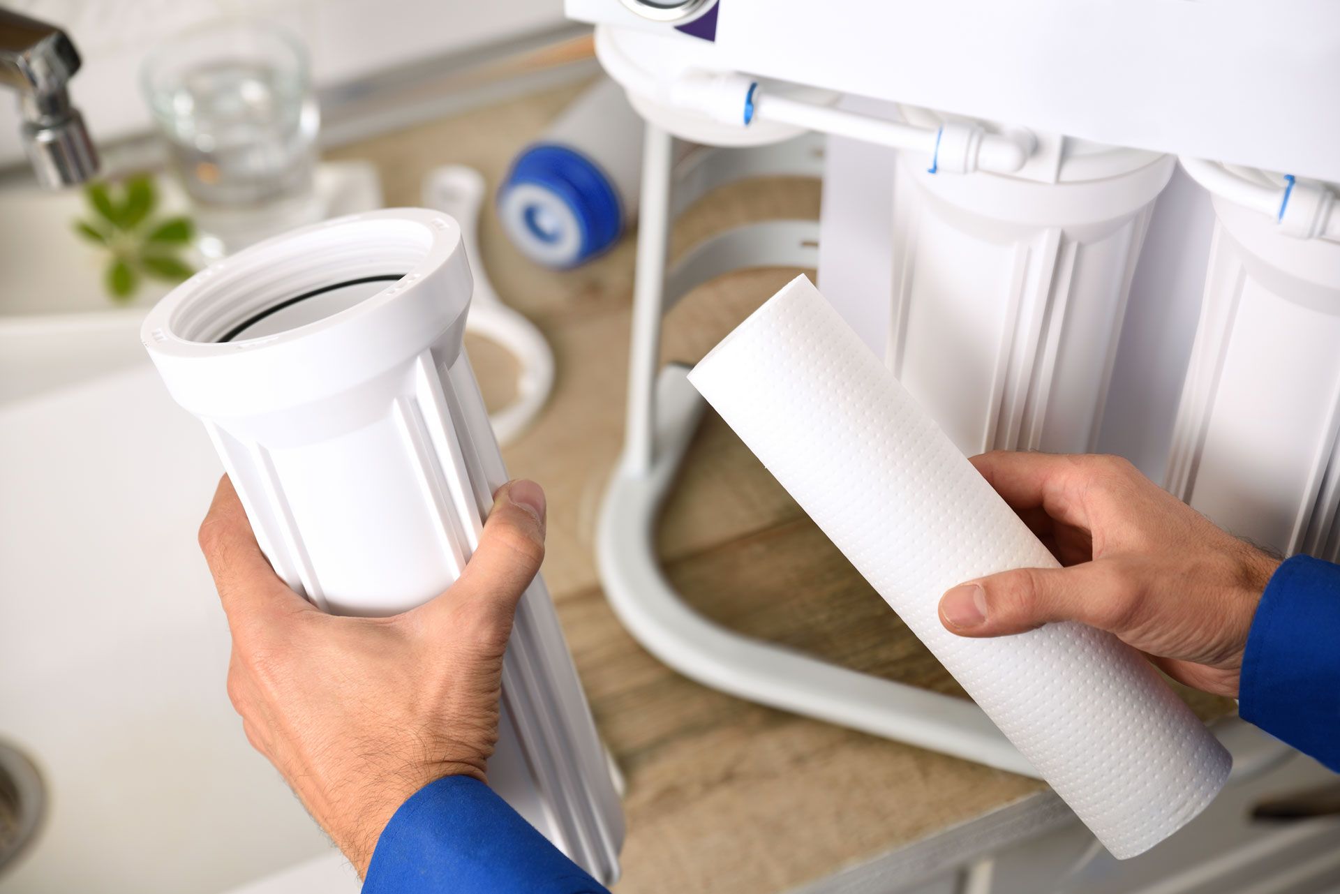 A man is holding a filter in his hands in front of a water filter.