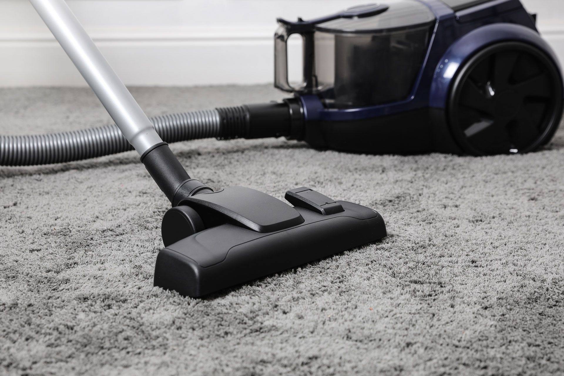 A vacuum cleaner is being used to clean a carpet.