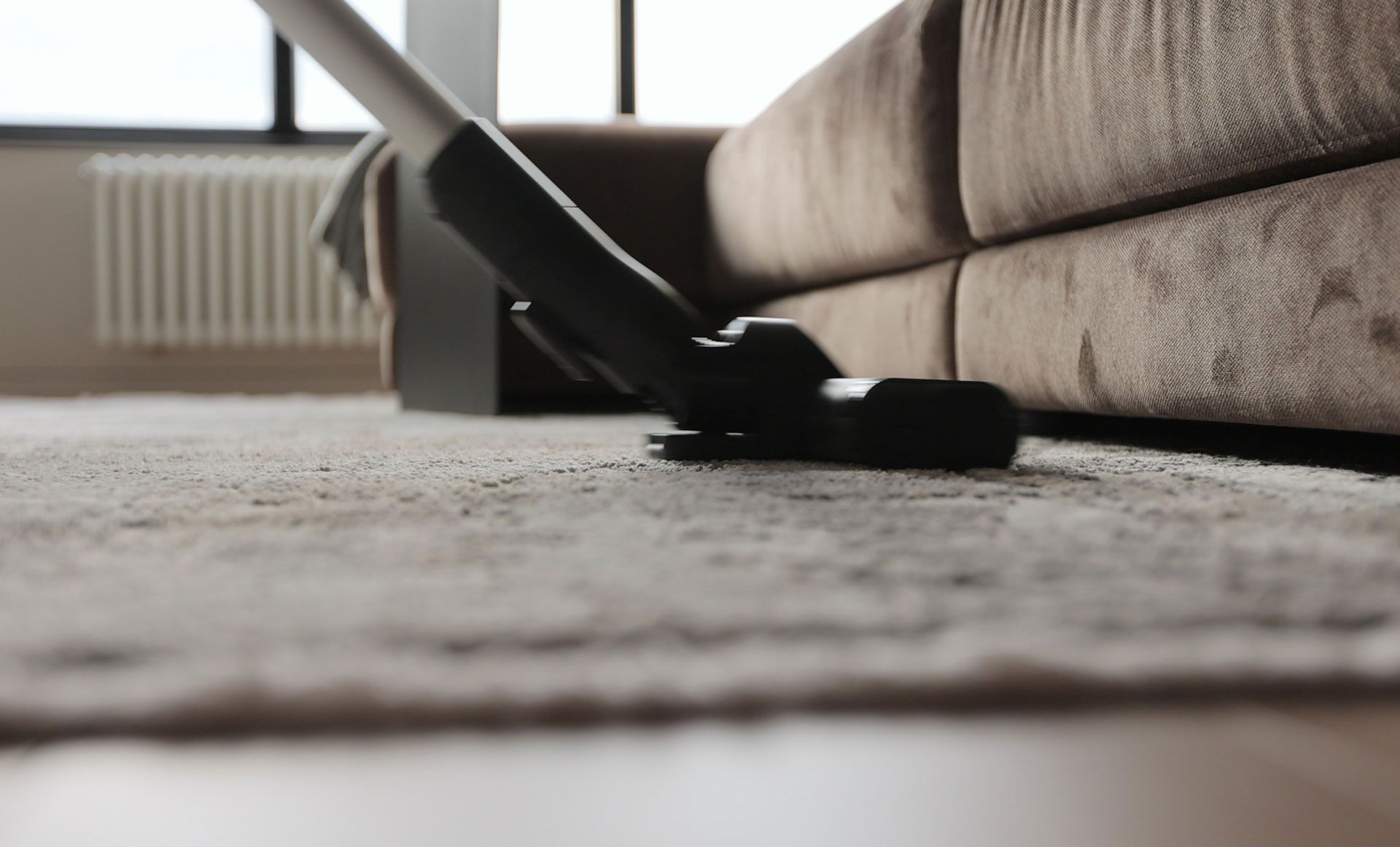 A vacuum cleaner is being used to clean a carpet in a living room.