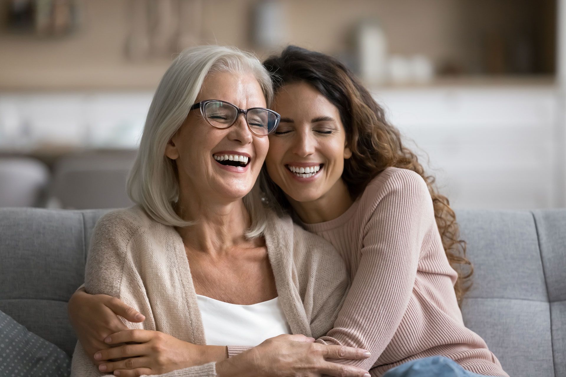 A young woman is hugging an older woman on a couch.