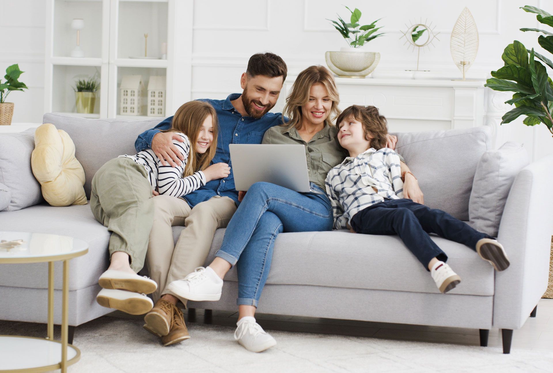 A family is sitting on a couch using a laptop computer.