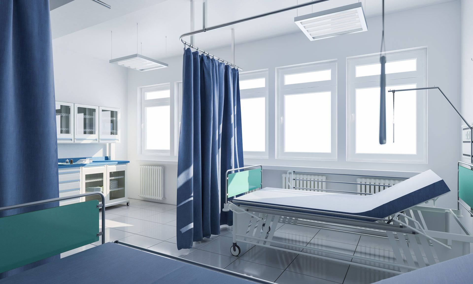 A hospital room with a bed and blue curtains.