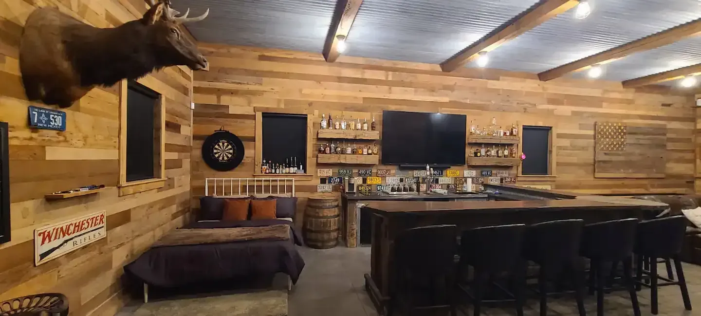 A large room with a deer head on the wall and a bar.