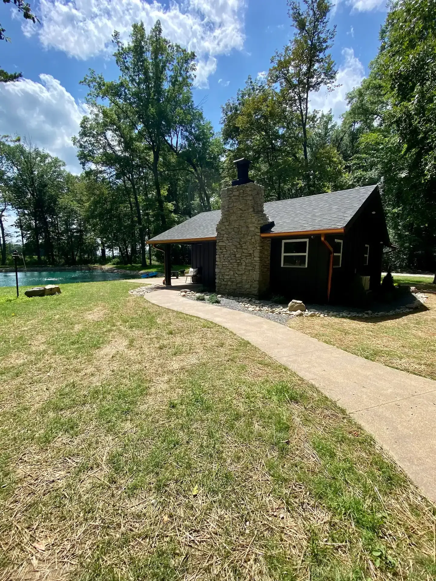 A small cabin with a stone chimney is sitting in the middle of a grassy field.