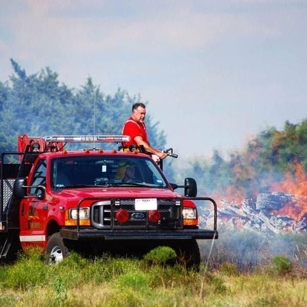 A man is sitting on the back of a red truck.