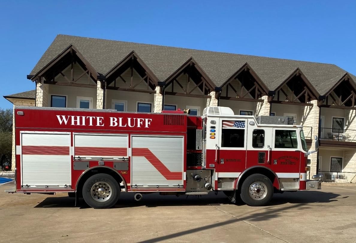 A white bluff fire truck is parked in front of a building