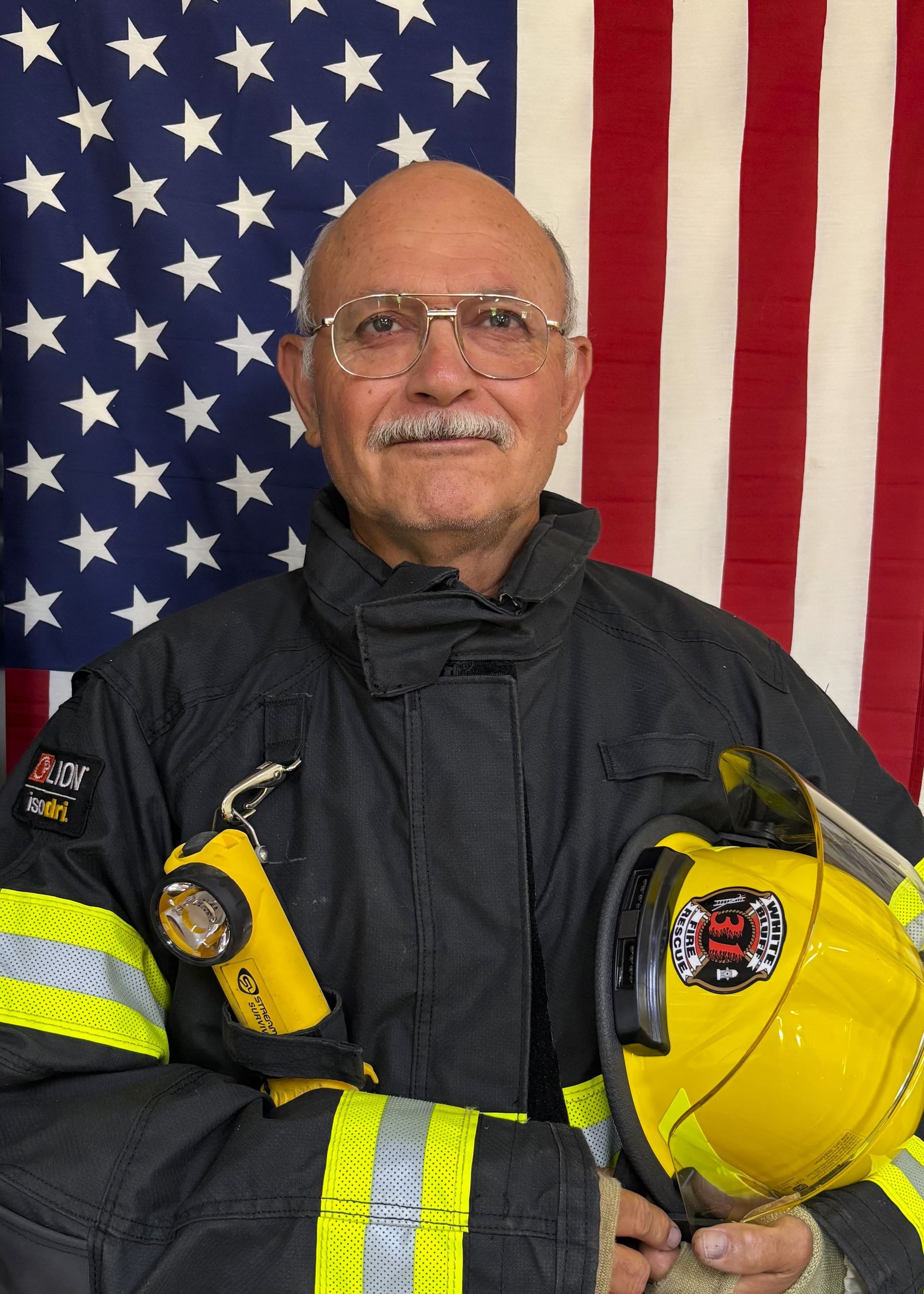 A man in a fireman 's uniform holds a helmet that says white dept
