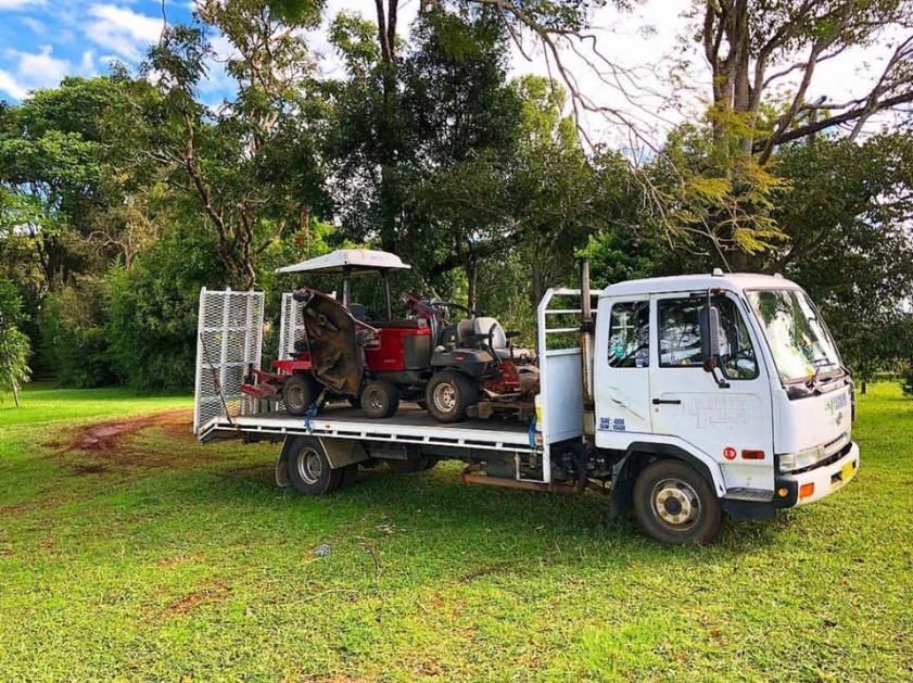 A White Truck With a Tractor on the Back is Parked in a Grassy Field — 4WD Slashing & Large Area Mowing In Byron Bay, NSW