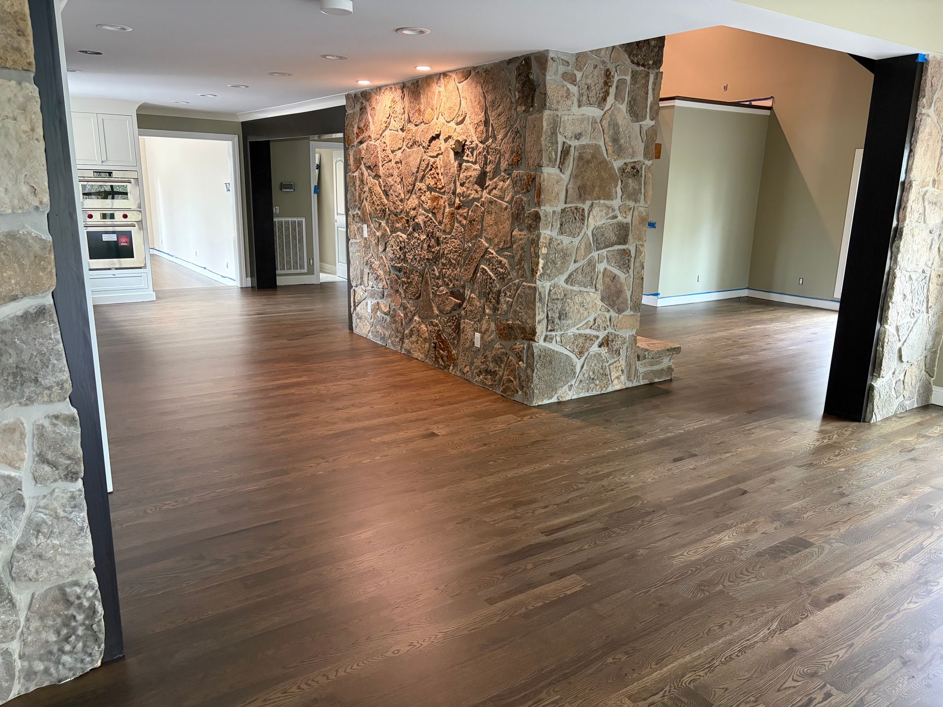 Empty modern living room with wood floors and a stone accent wall.