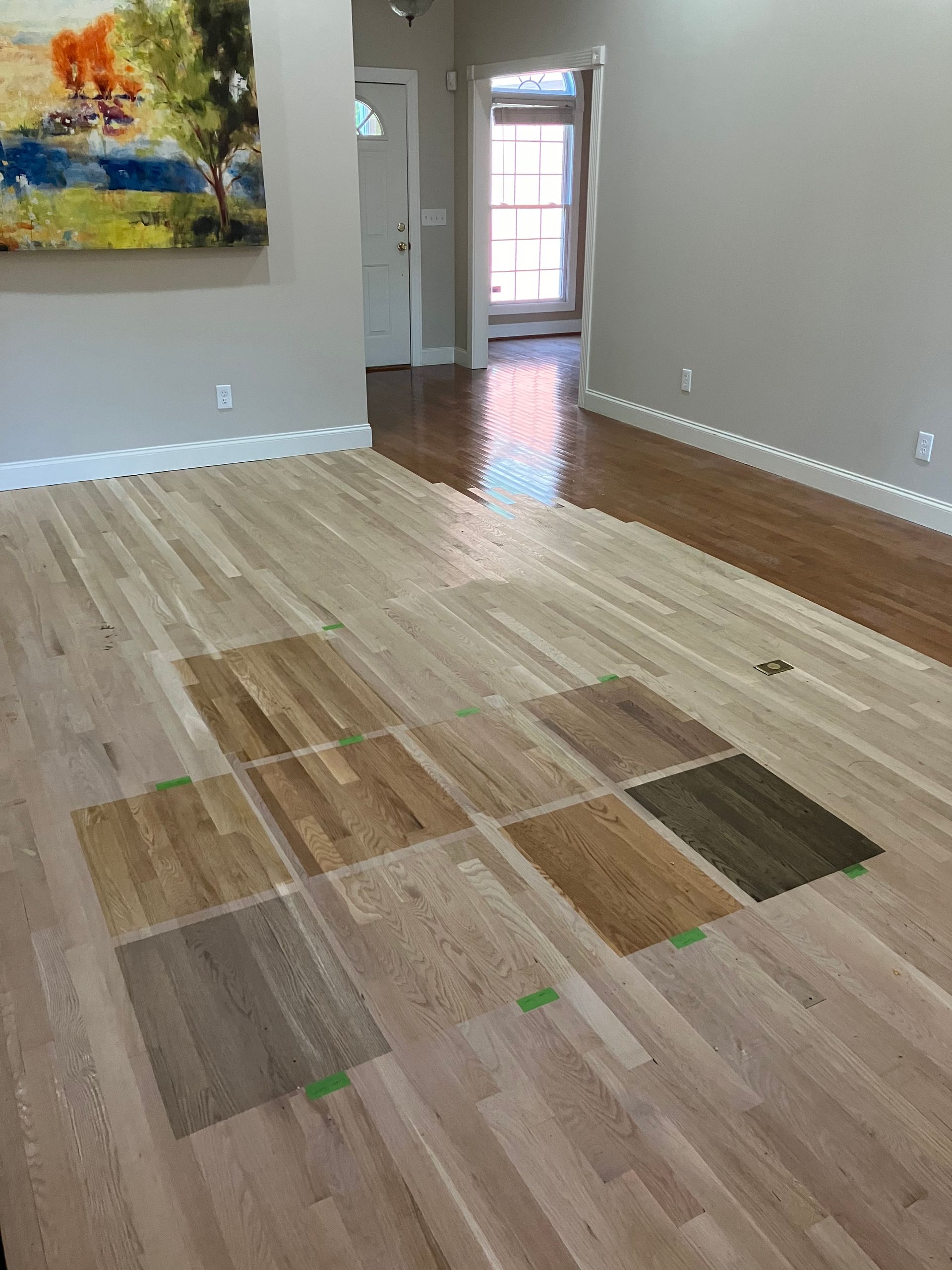 Living room with unfinished hardwood floor and a colorful painting on the wall