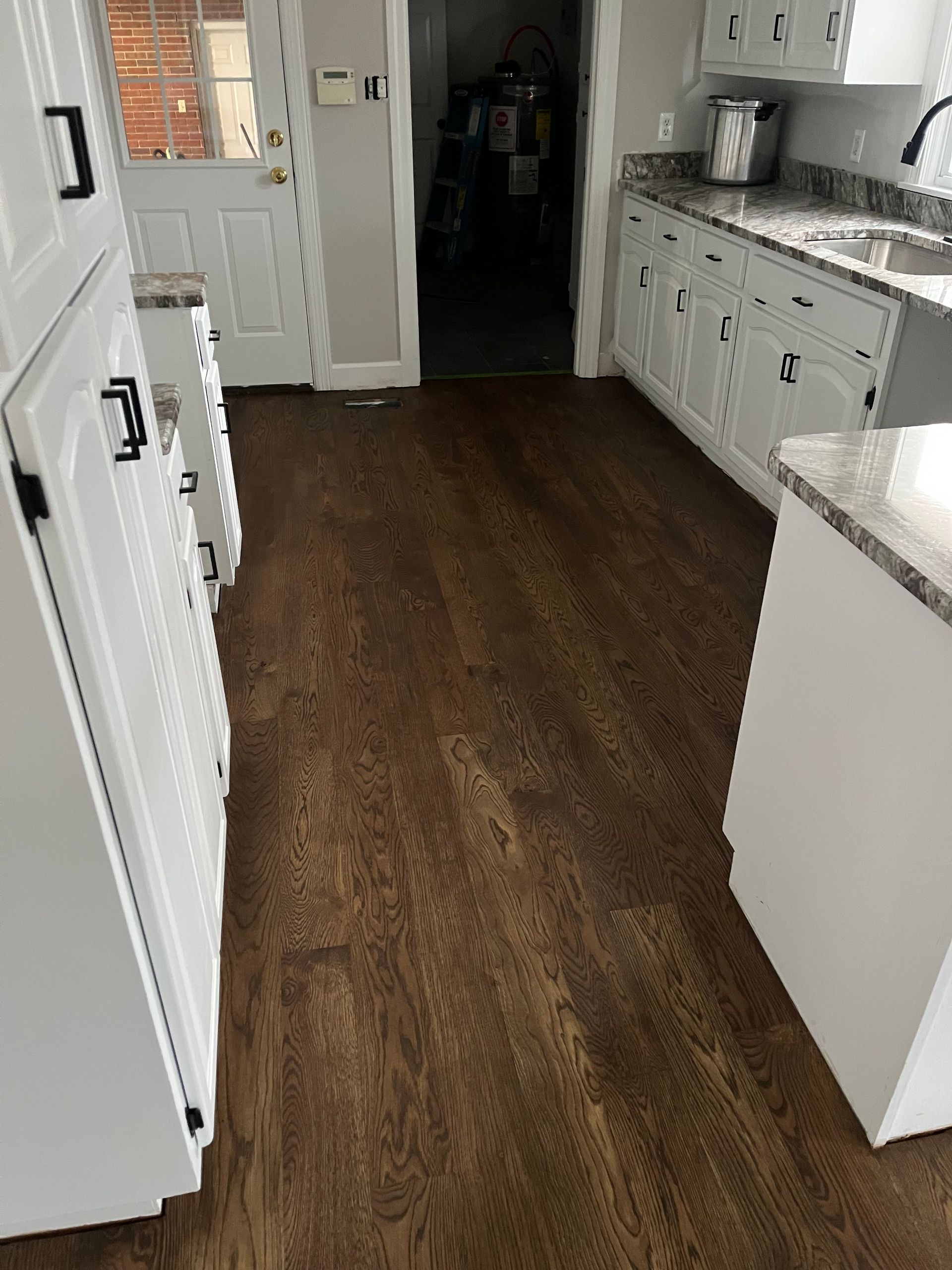 White kitchen with dark wood floors, white cabinets, and a granite countertop.